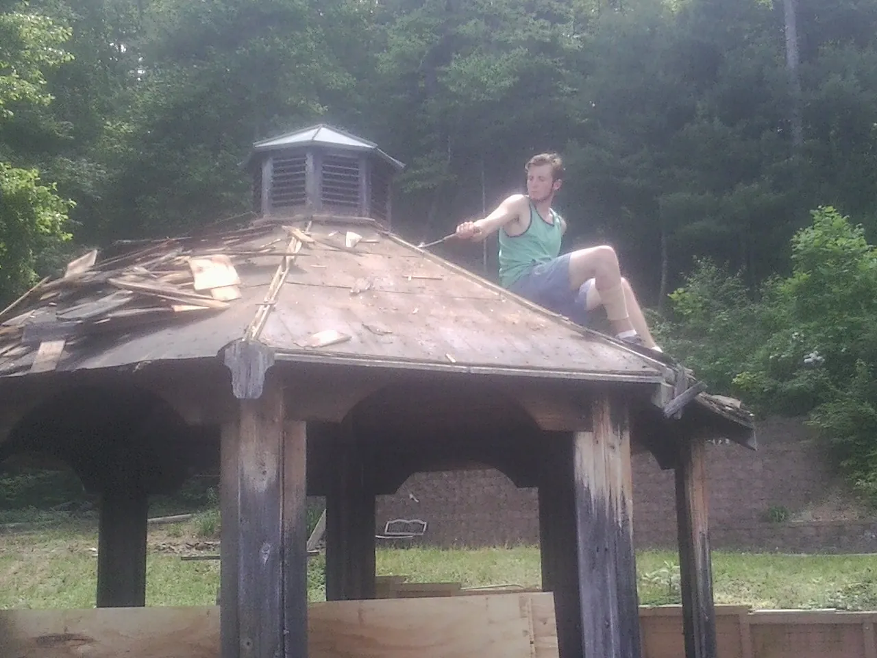 Tearing the old roof off a wooden gazebo before new shakes in Alpha
