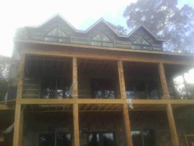 Dormers and porch framing on a large log home under construction — Roof Coating work by our crew in Alpha