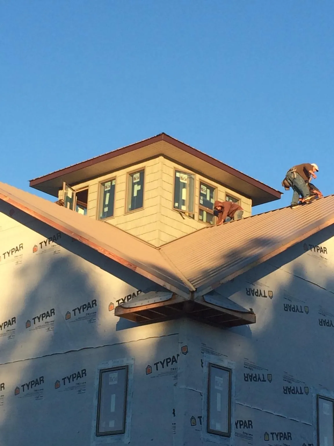 Roofers working around a rooftop cupola on a new metal roof at sunset — Roof Waterproofing in Alpha by Roofing Brothers